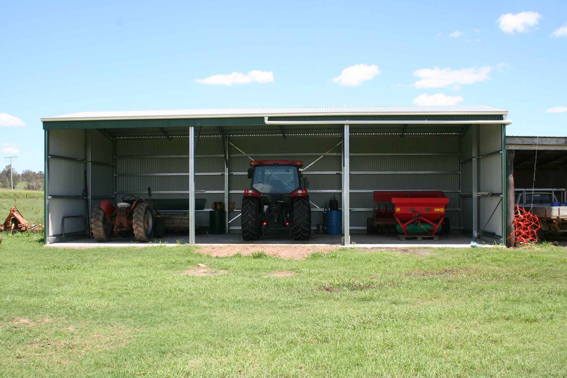 A Tractor Is Parked In A Shed In A Grassy Field – South Kempsey NSW - Fair Dinkum Builds Macleay Valley Sheds