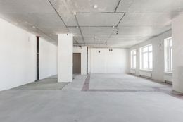 Empty, unfinished room with white walls, concrete floor and ceiling, several windows.