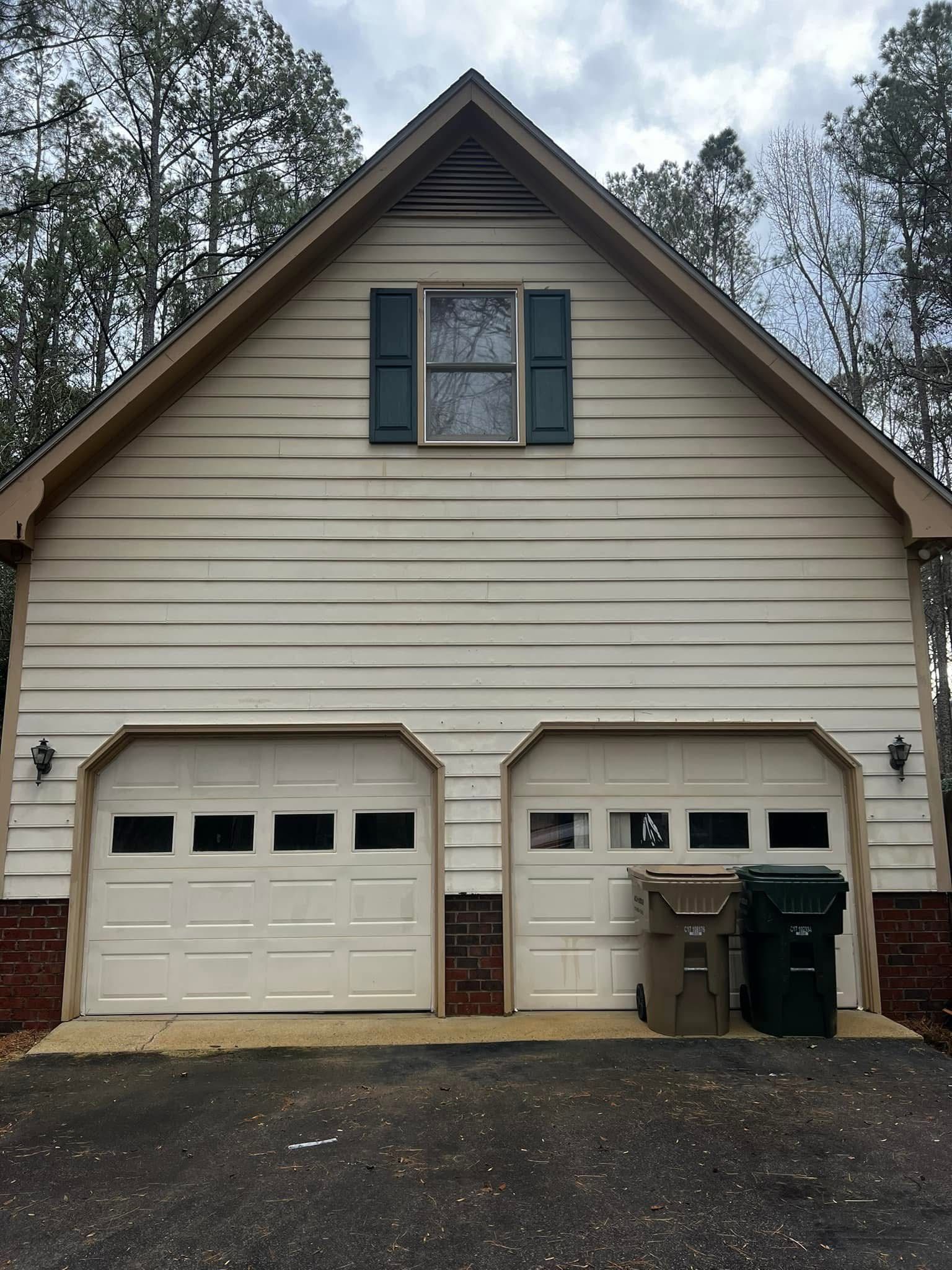 A large white house with two garage doors and a window.