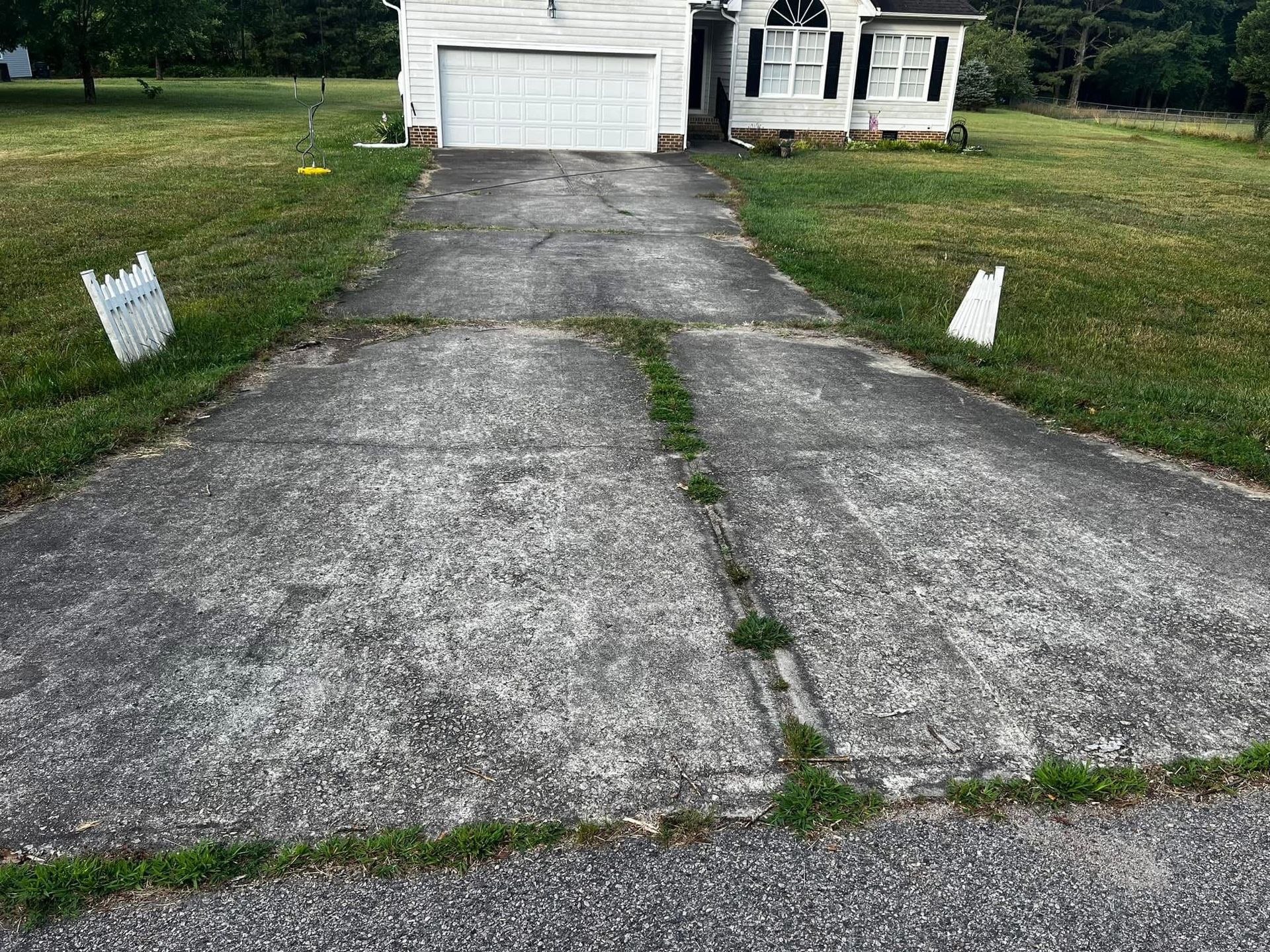 A concrete driveway leading to a house with a white garage door.