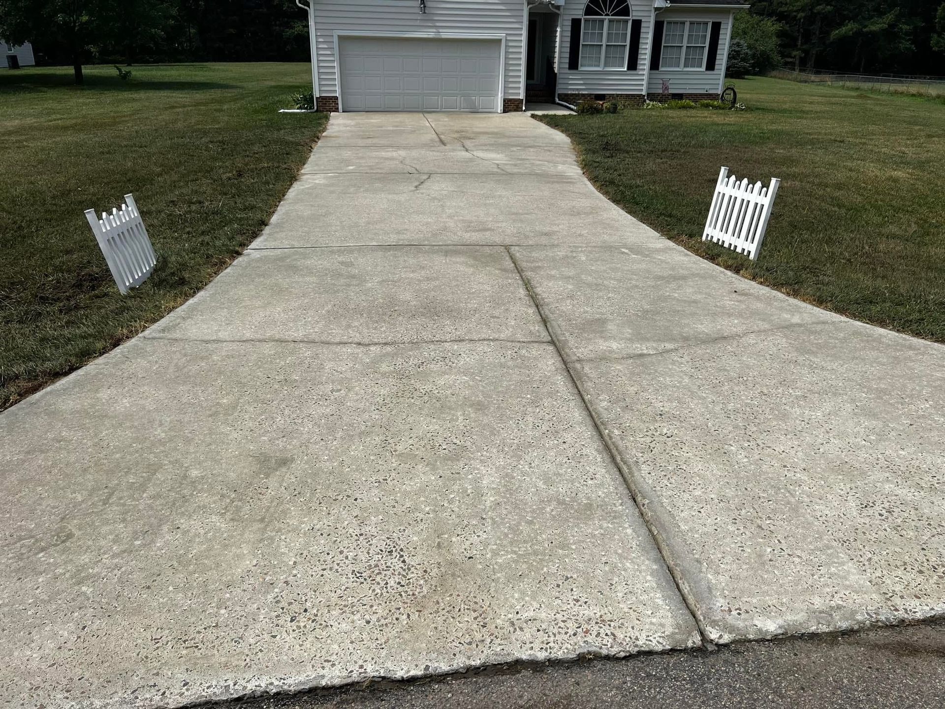 A concrete driveway leading to a house with a white garage door.