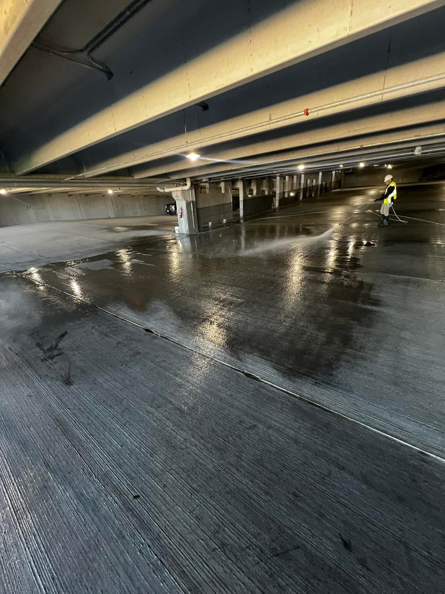A person is cleaning a parking garage under a bridge.