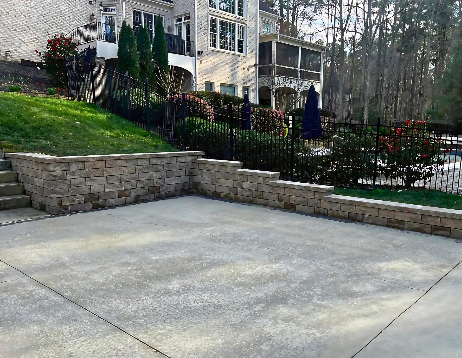 A concrete driveway with a stone wall in front of a house.