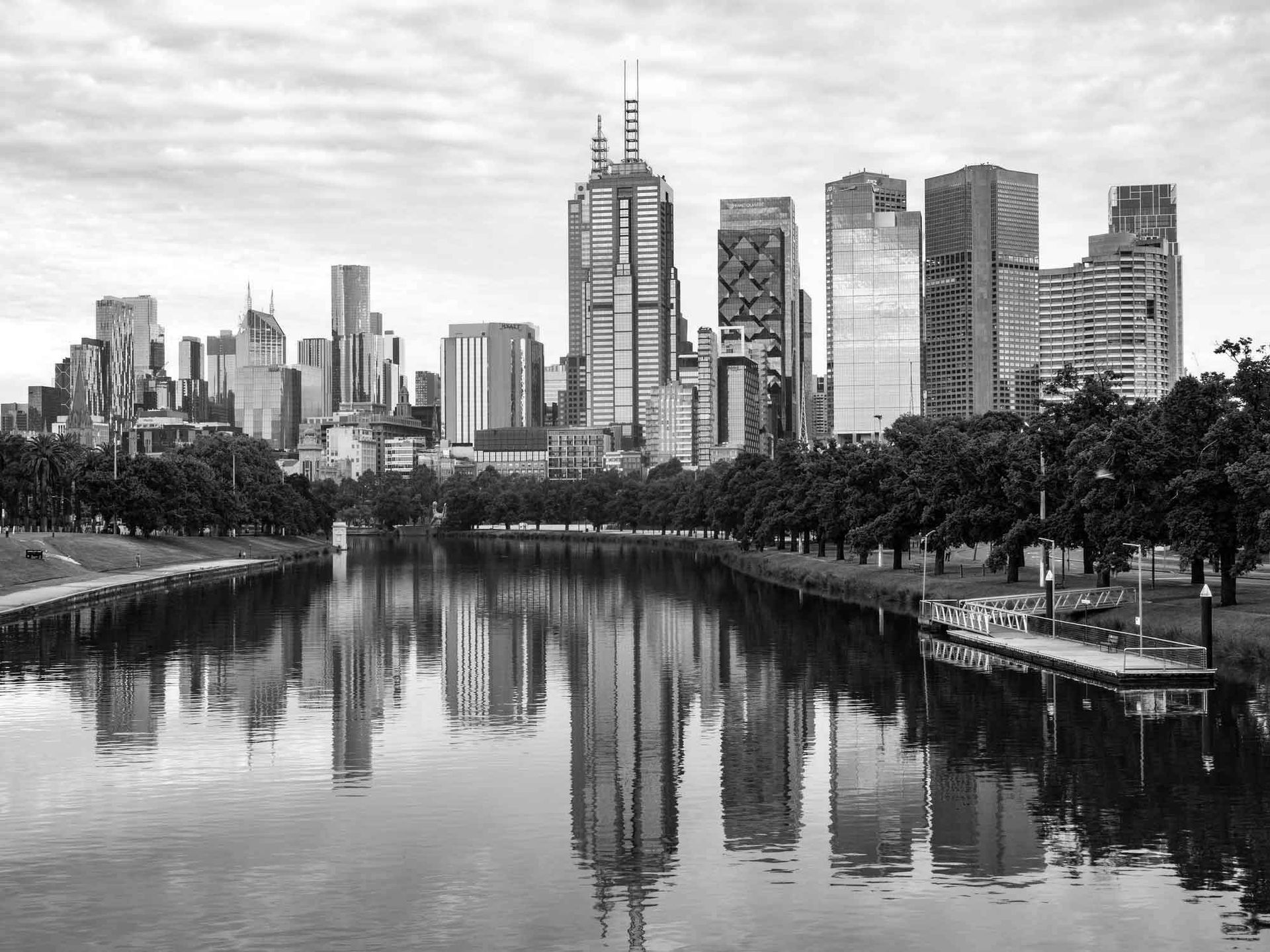 A black and white photo of a city skyline reflected in a body of water