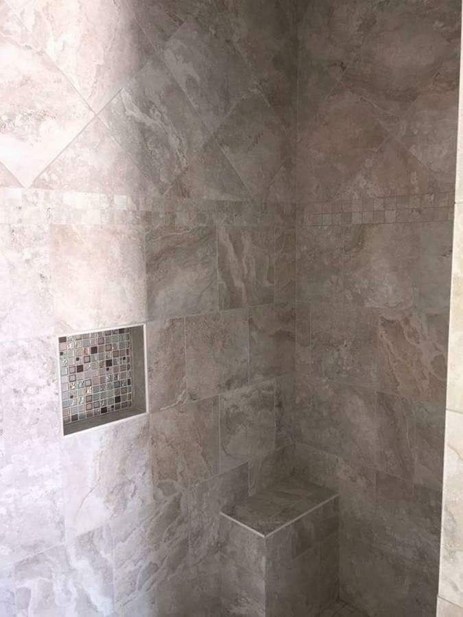 A bathroom with a shower stall and a shelf in the wall.