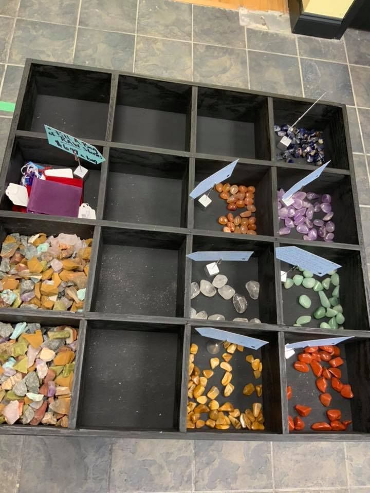 A display of crystals and stones in black compartments, with price tags.