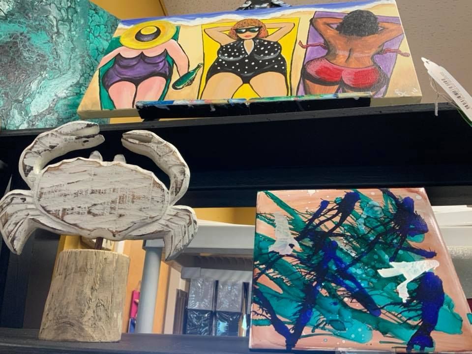 Art display: paintings of women sunbathing and abstract art, with a crab sculpture.