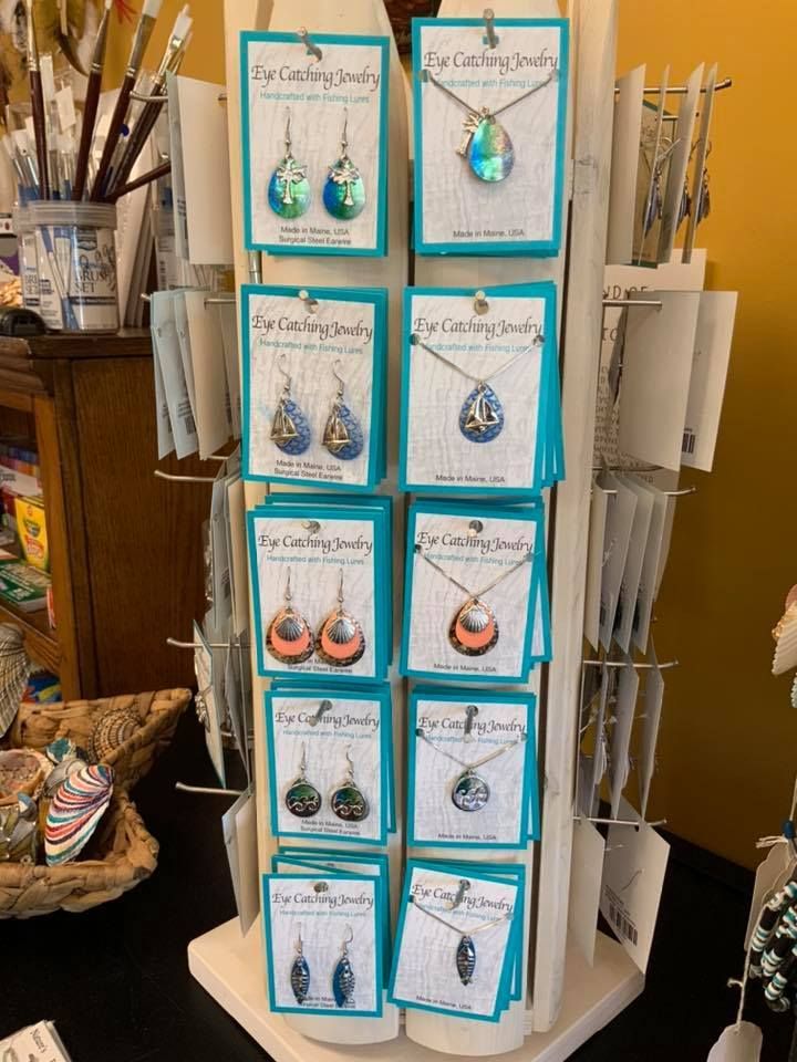 Jewelry display stand with teal-backed earring and necklace cards; earrings and necklaces on a cream stand.