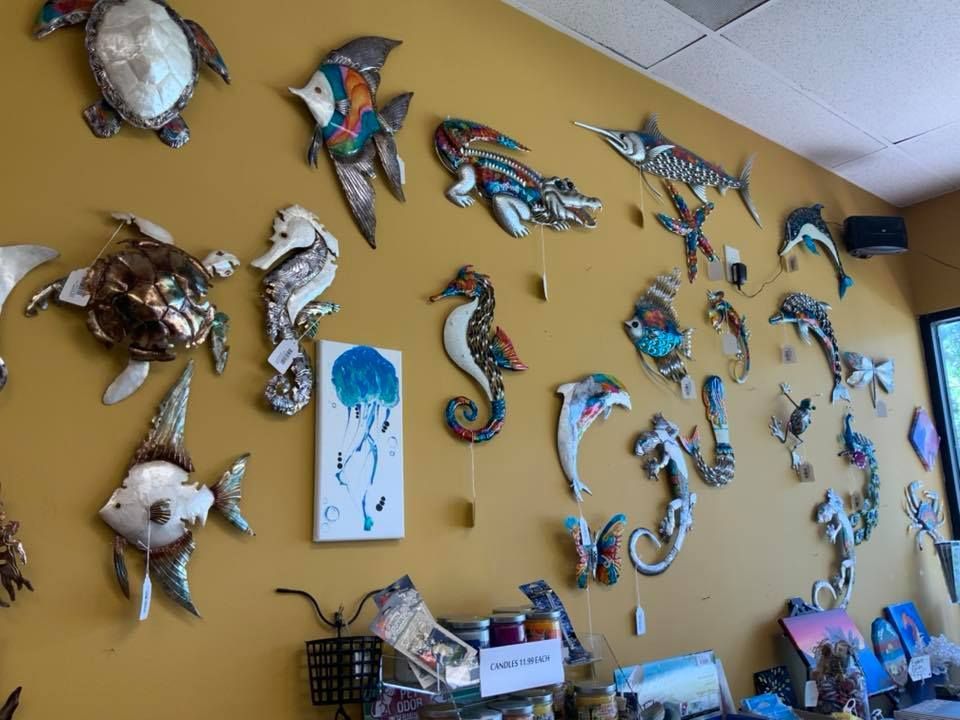 Yellow wall with various metal sea creature art, including fish, turtles, and seahorses, displayed.
