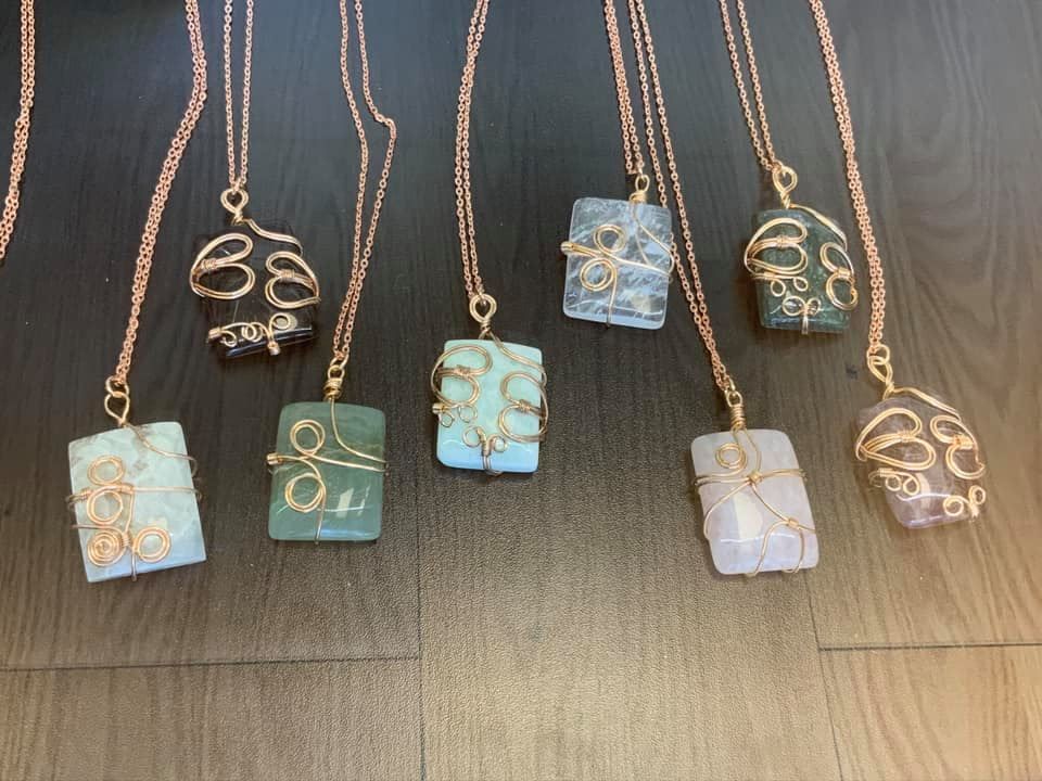 Handmade gemstone necklaces in various colors, wire-wrapped in gold chain in a USA shop.