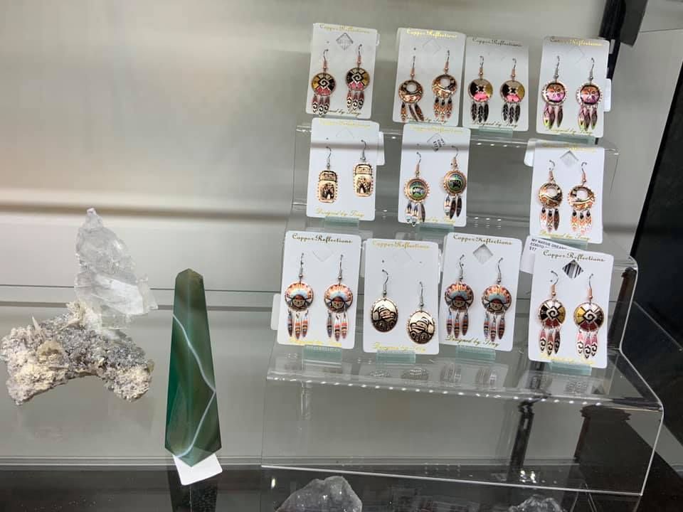 Display case with earrings on cards, plus green and white stone sculptures in a USA shop.
