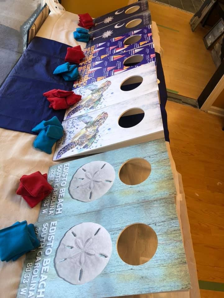 Cornhole game boards with blue and red bean bags, coastal designs in a USA shop.