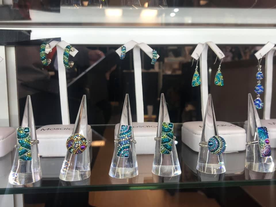 Jewelry display with rings and earrings featuring blue and green designs in a USA shop.