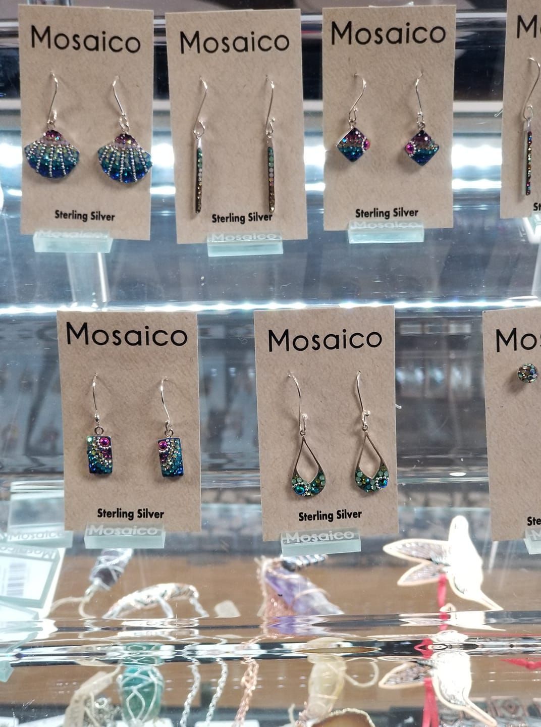 Display of Mosaic earrings in a glass case; sterling silver with colorful accents in a USA shop.