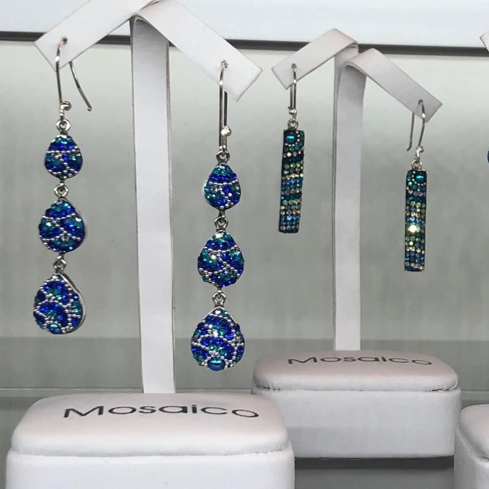 Earrings on white display stands, featuring blue mosaic gems in a USA shop.