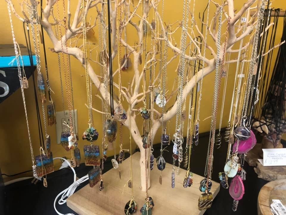 Necklaces with colorful pendants hang from a wooden display in a shop in a USA shop.