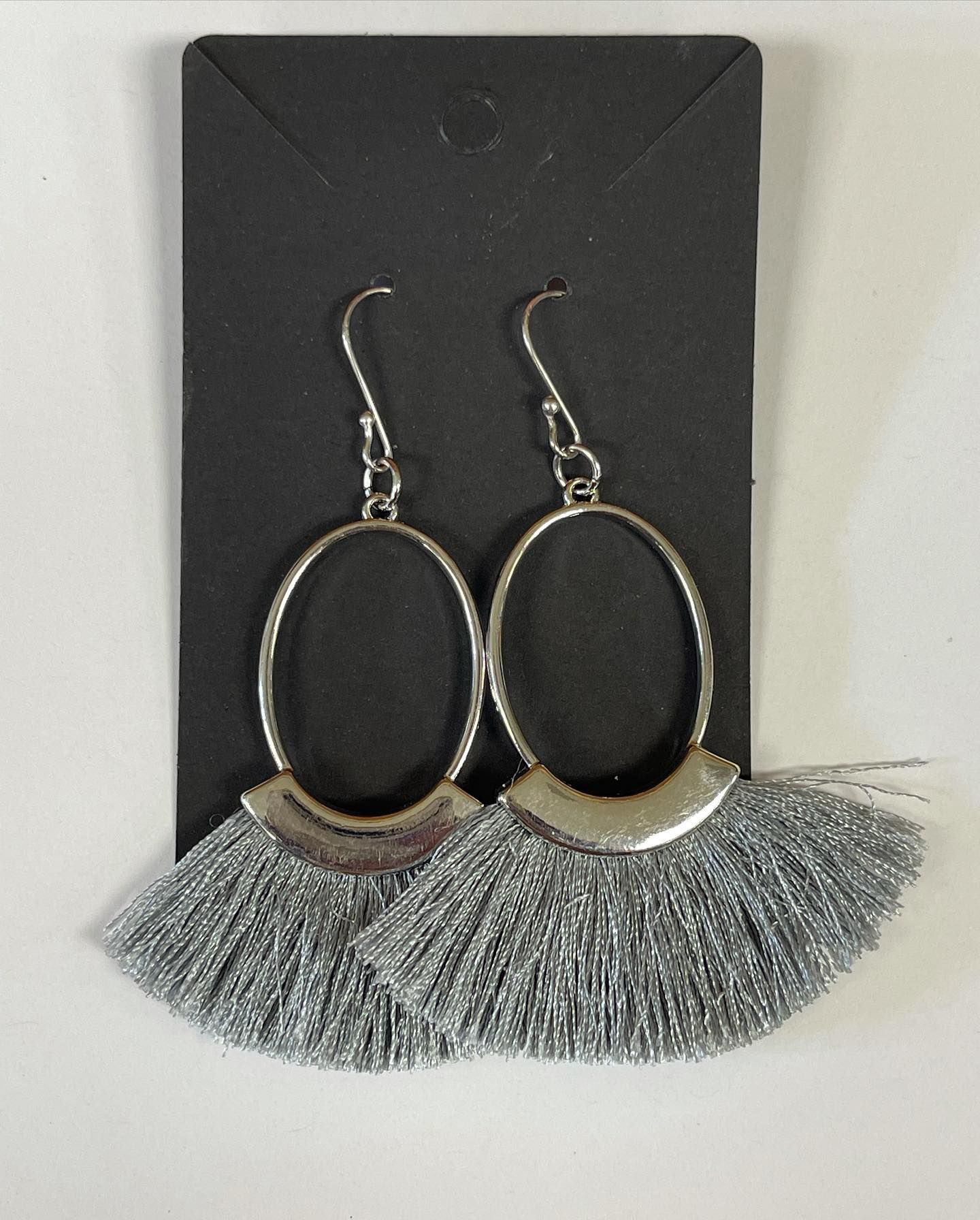 Silver tassel earrings on a black display card.