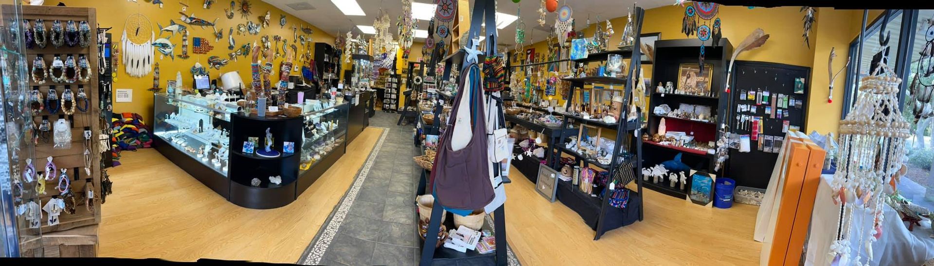 Interior shop view: jewelry displays, merchandise on shelves, yellow walls, wood floor.