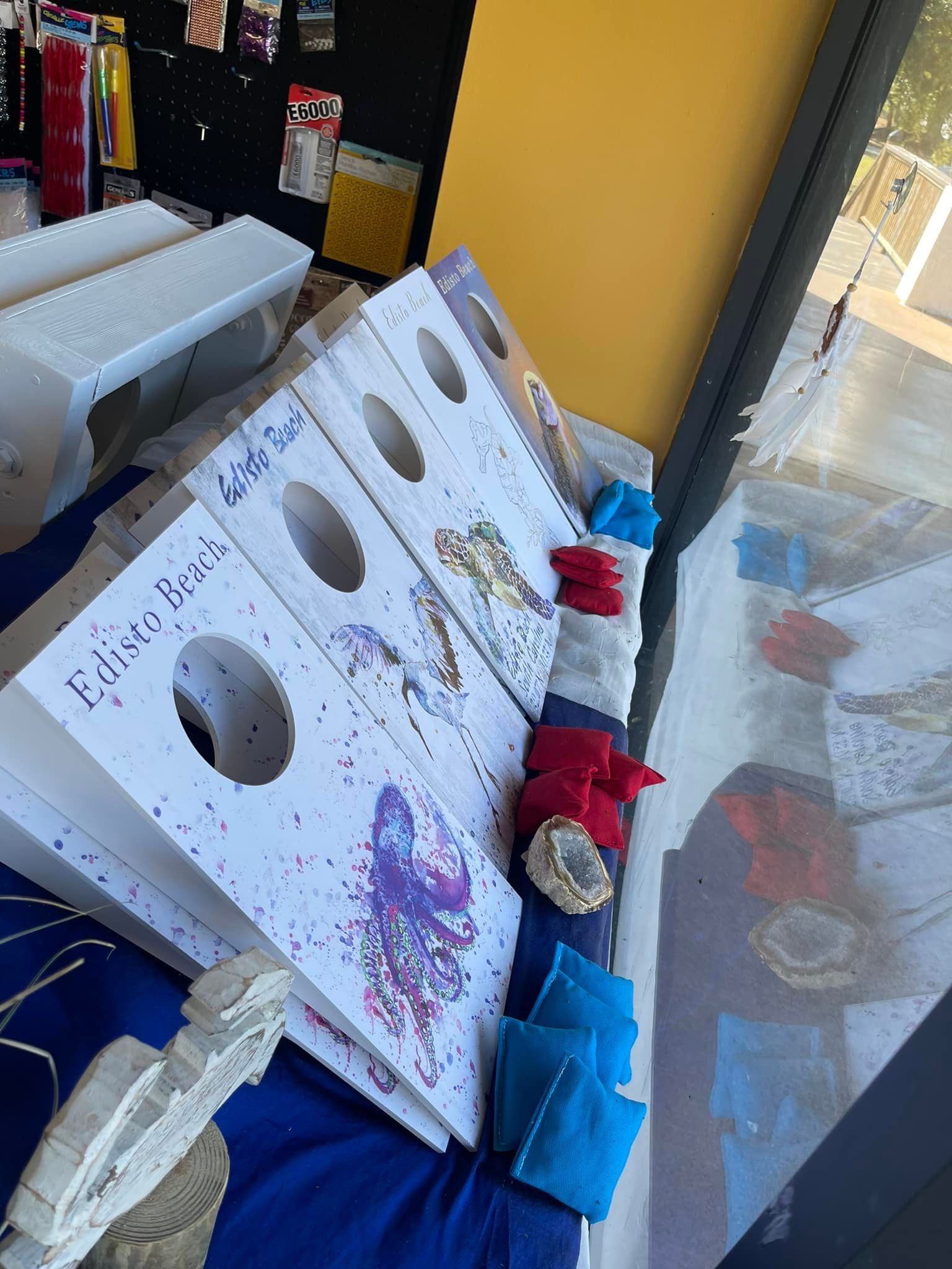 Cornhole boards with butterfly art, bean bags, in a store setting.