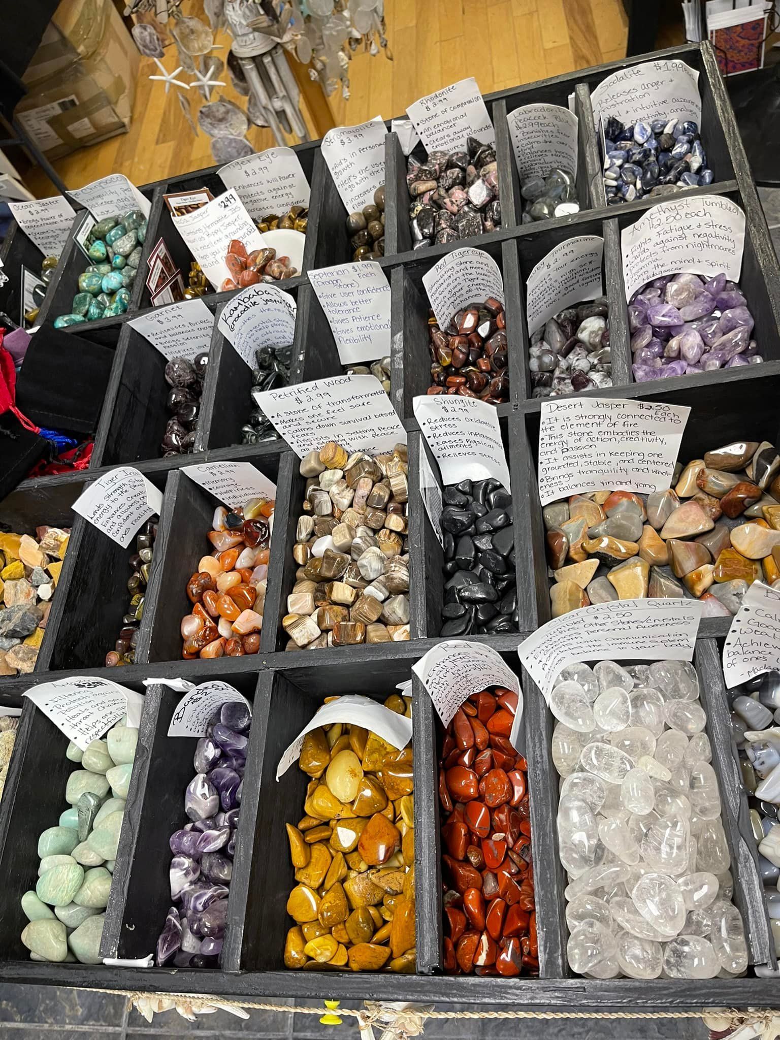 Display of various colorful gemstones in labeled compartments.