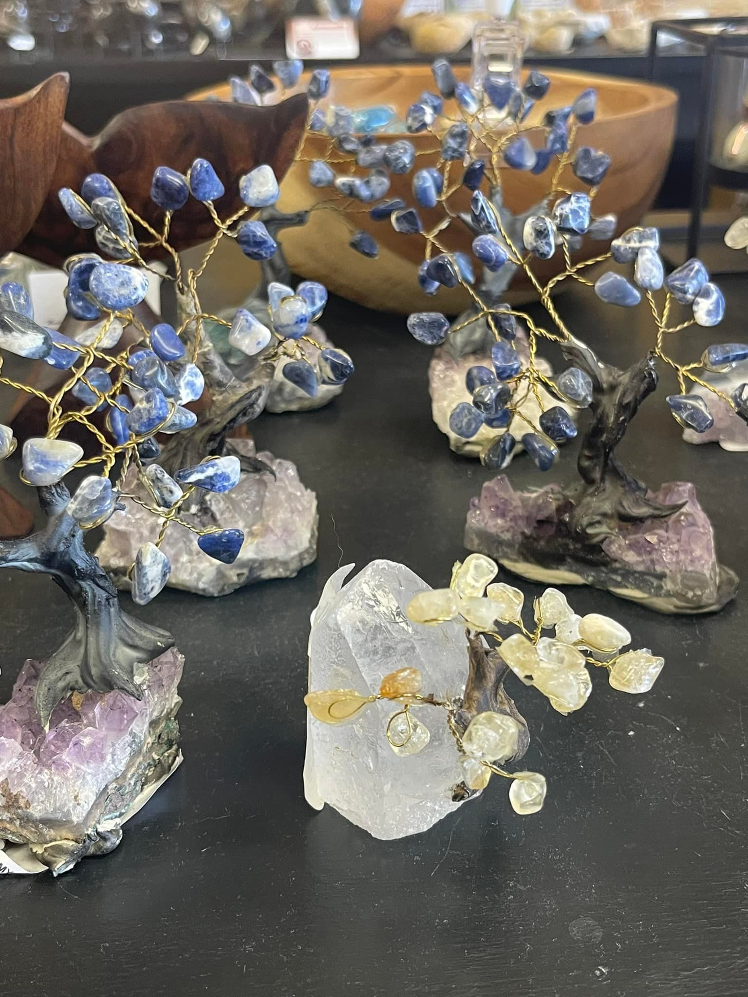 Crystal trees with blue and yellow gemstone leaves on amethyst and quartz bases.