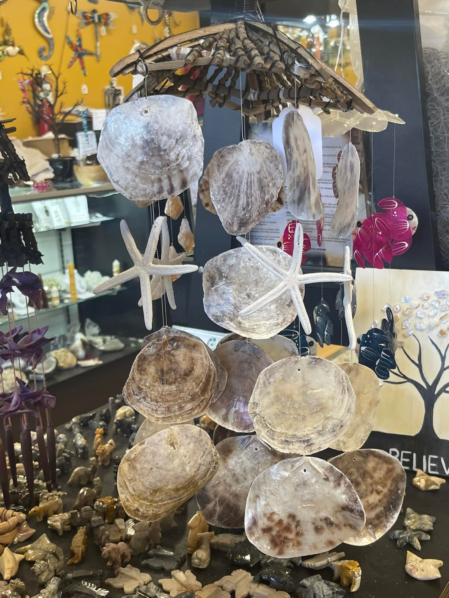 Display of hanging shell ornaments and starfish in a shop setting.