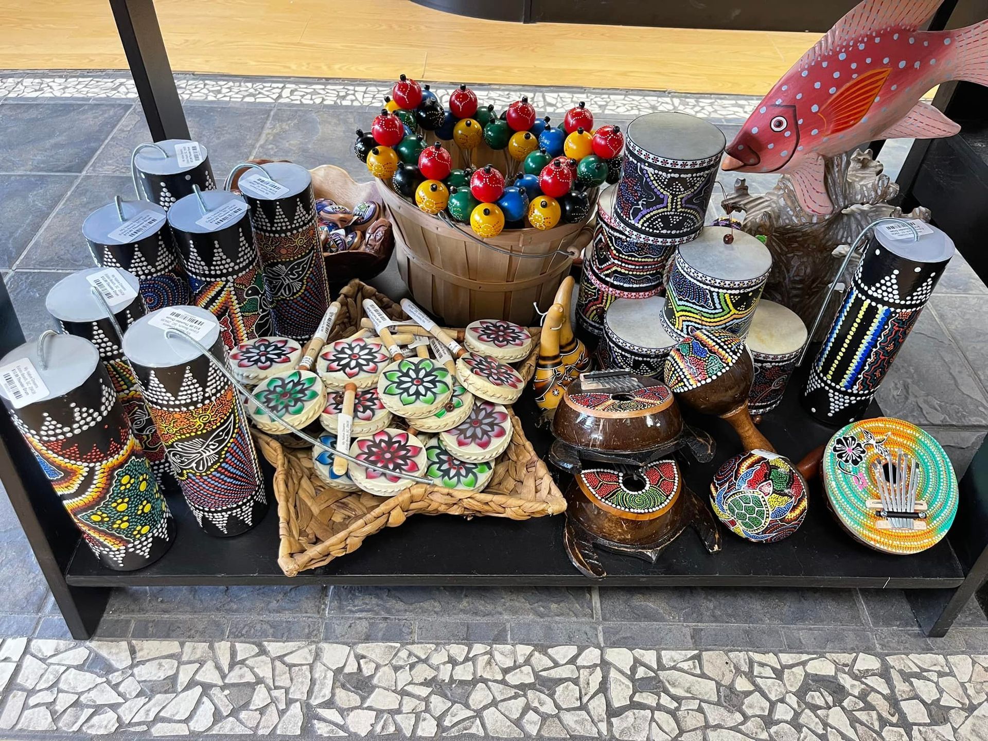 Display of colorful handcrafted drums and musical instruments at an outdoor market stall.