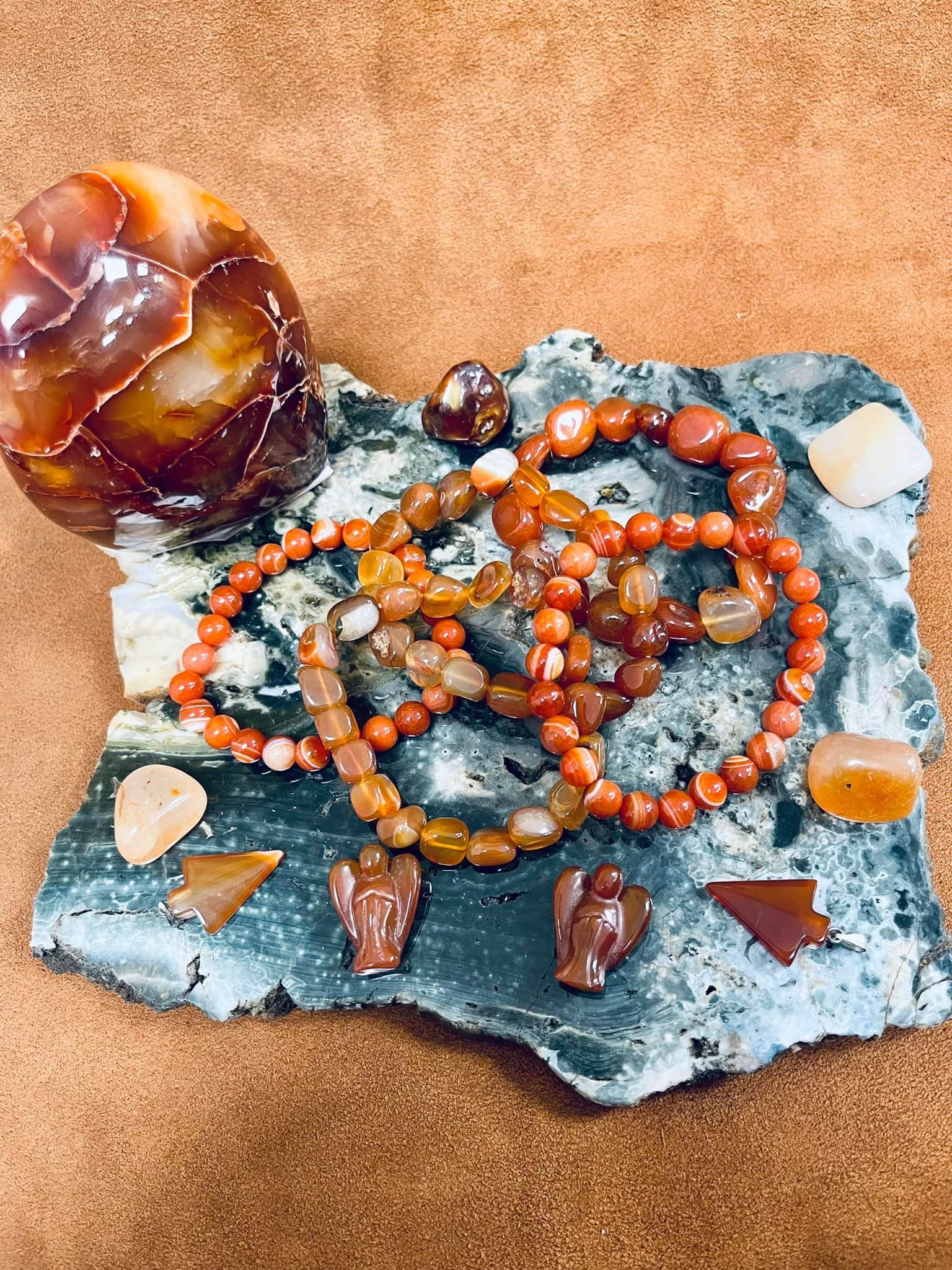 Carnelian beads, figurines, and stones on a textured slab and brown surface in a USA shop.
