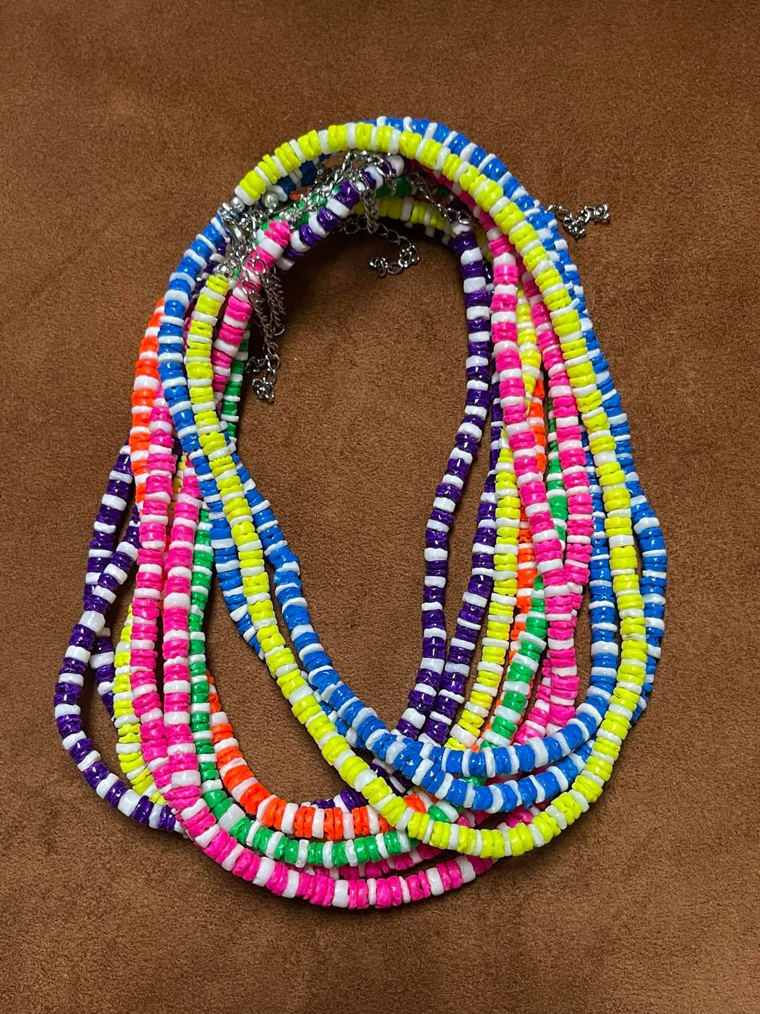 Pile of colorful, beaded necklaces in various bright colors on a brown surface.