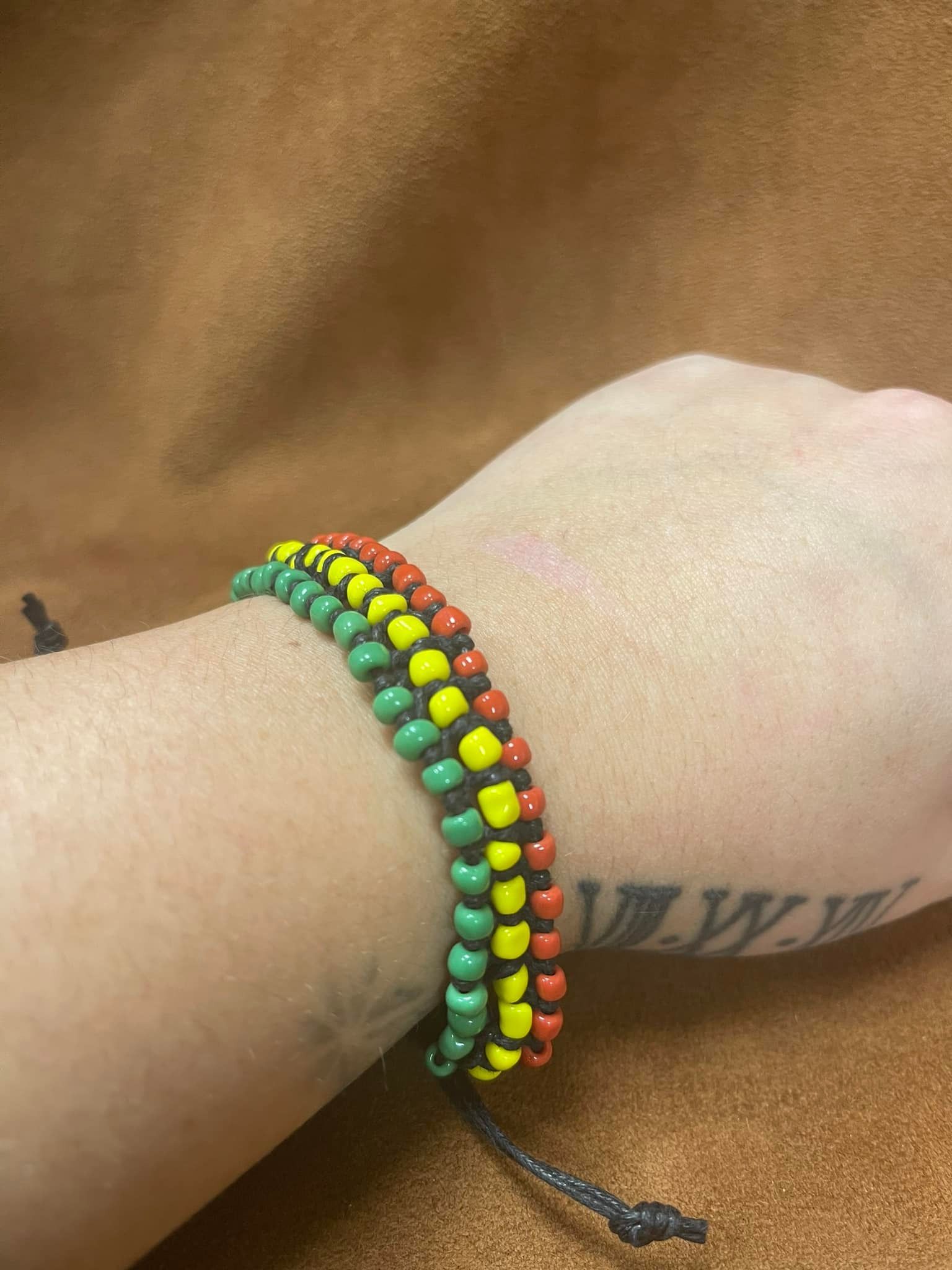 Wrist with a Rastafarian-themed beaded bracelet in red, yellow, and green.