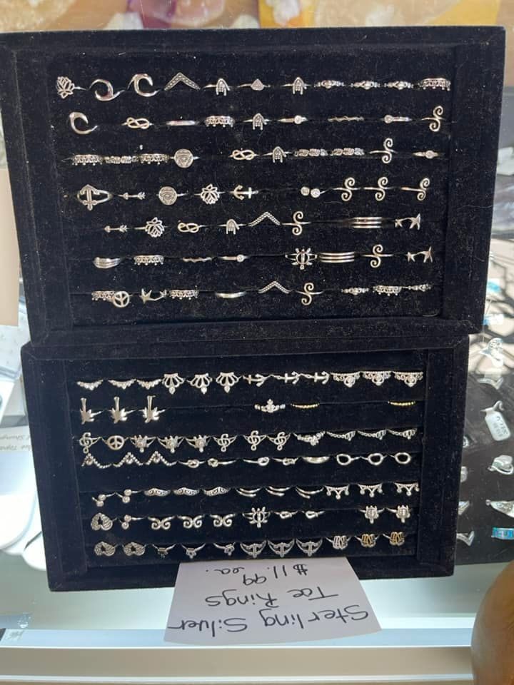 Two black velvet trays of silver toe rings, displayed for sale.