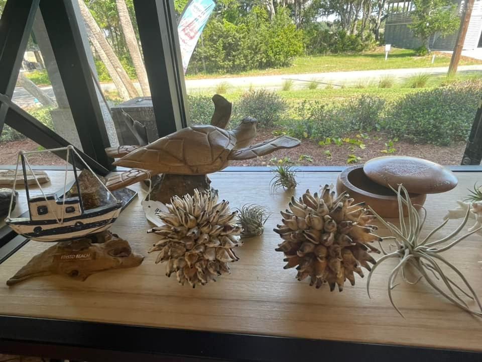 Wooden turtle and nautical decor on a windowsill, with greenery visible outside.