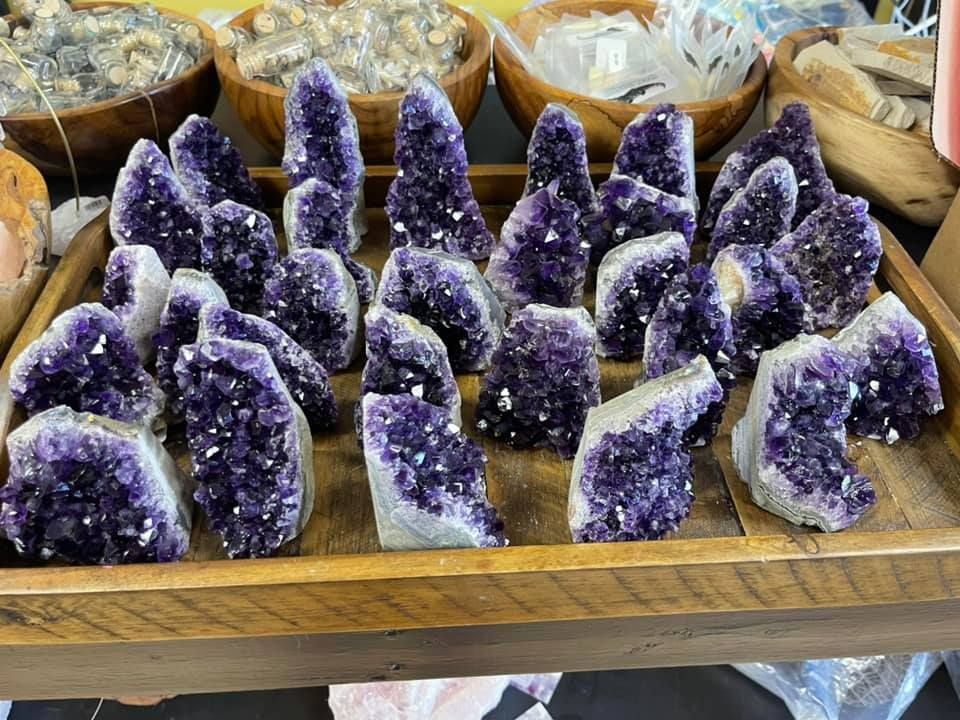 Purple amethyst crystal clusters displayed in a wooden tray.