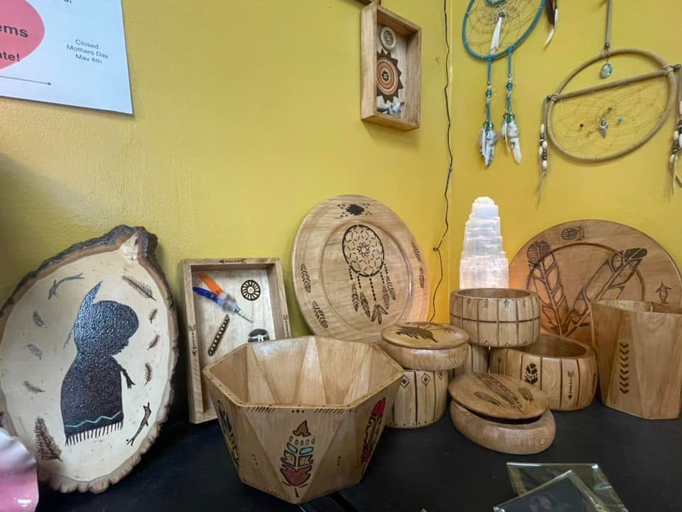 Wooden crafts, including bowls and artwork, displayed on a yellow wall with dream catchers.