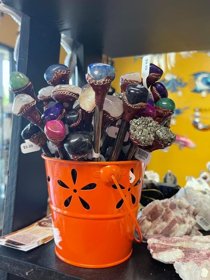 Orange bucket filled with gemstone-topped wands, on display at a shop.