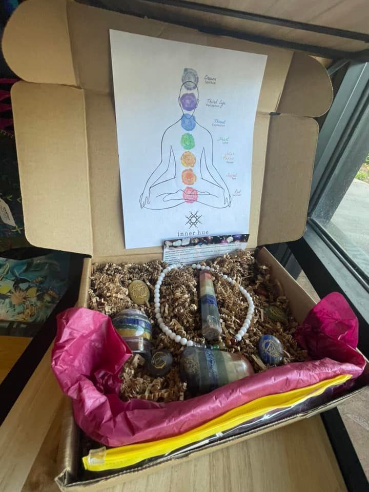 Box containing crystals, a necklace, and a diagram of chakras on a sheet of paper.