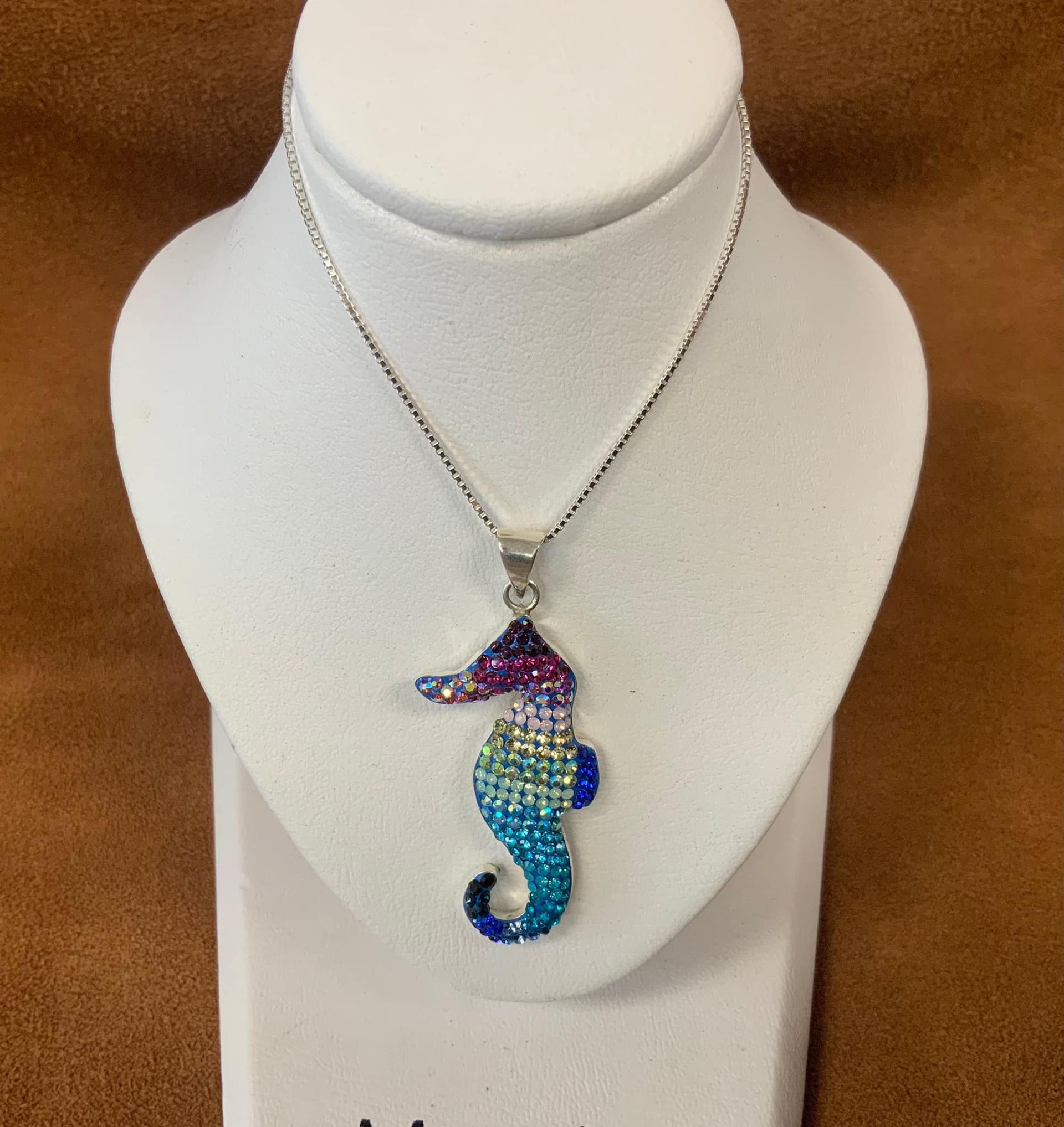 Seahorse pendant necklace with blue, purple, and teal gems on a white mannequin.
