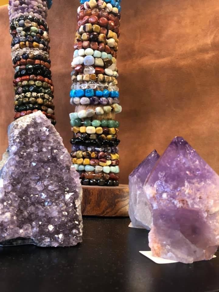 Amethyst crystals and stacked gemstone bracelets on display.
