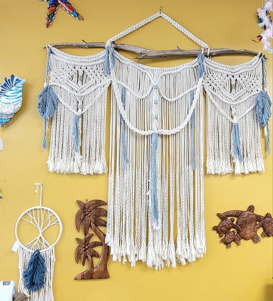 Macrame wall hanging with blue and white rope against a yellow wall, decorated with ocean-themed decor in a USA shop.