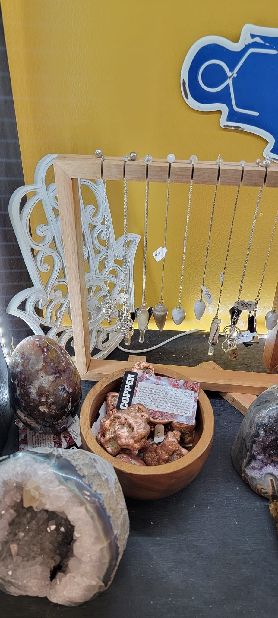 Jewelry display with necklaces and crystals on a table. Yellow background with blue drawing.