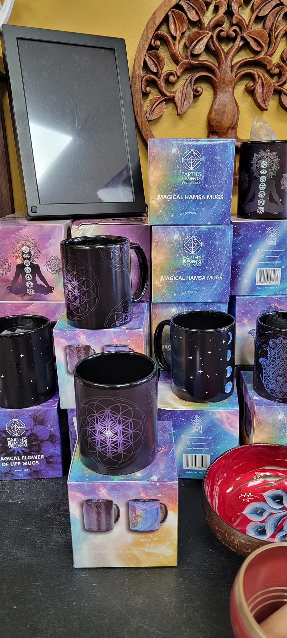 Mugs with starry designs on boxes, beside a frame and wooden carving.