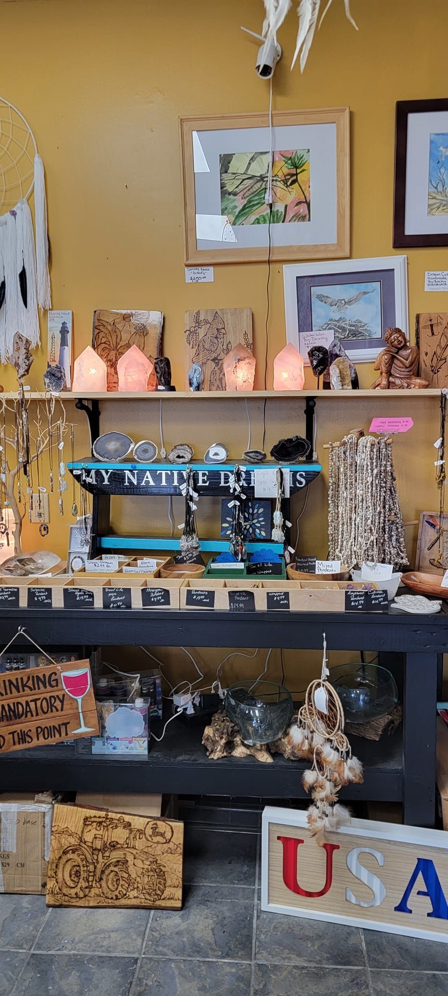 A shop display with shelves filled with merchandise, including art and jewelry. 