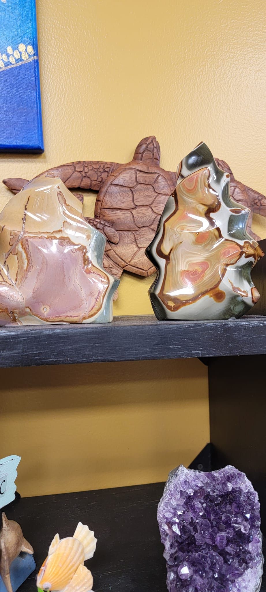 Ceramic sculptures, including a turtle, sit on a shelf. An amethyst crystal is below.