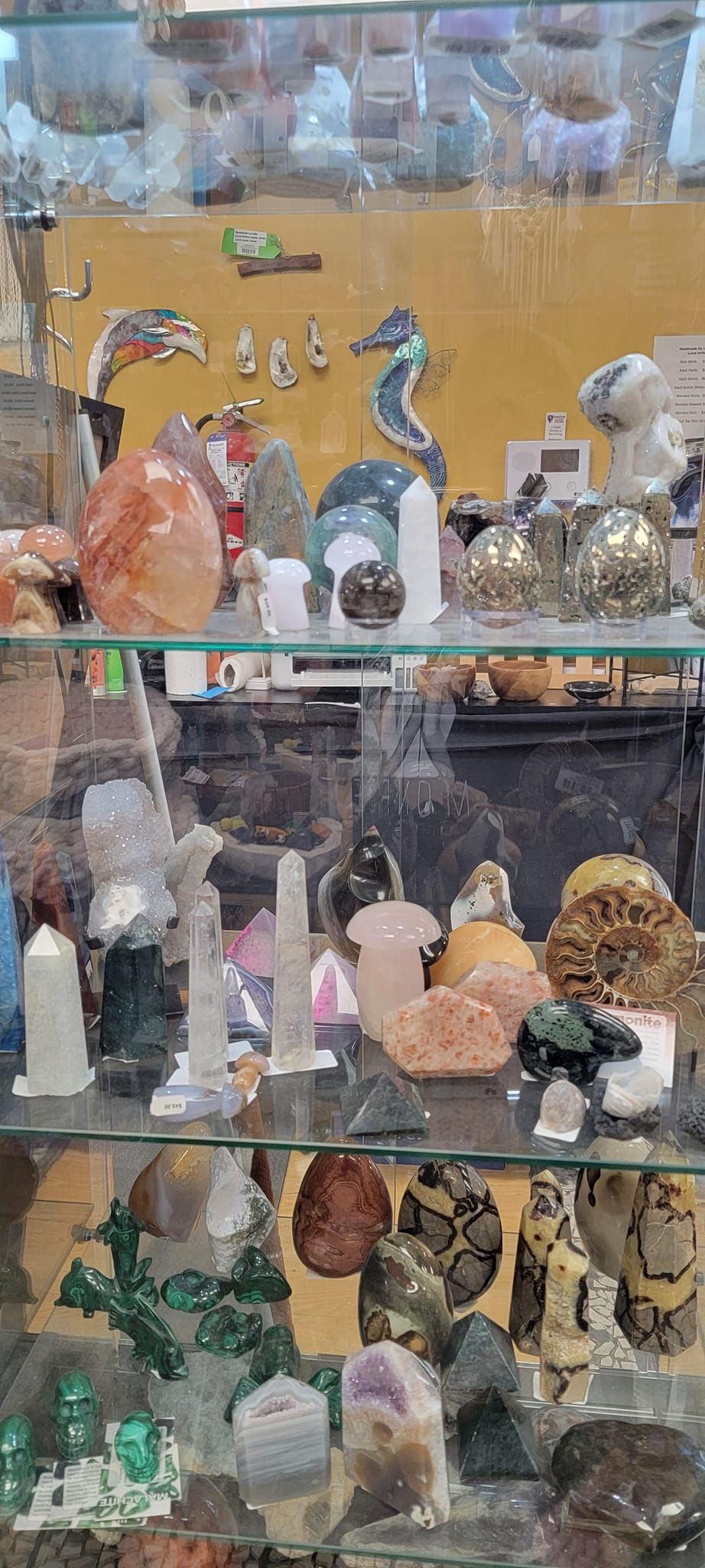 A display cabinet filled with various colorful polished gemstones and crystals for sale in a shop.