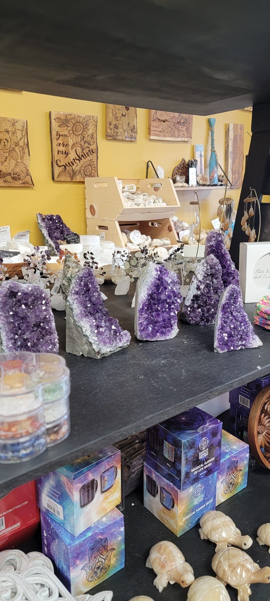 A store display with amethyst crystals, boxes with starry patterns, and shells on shelves.