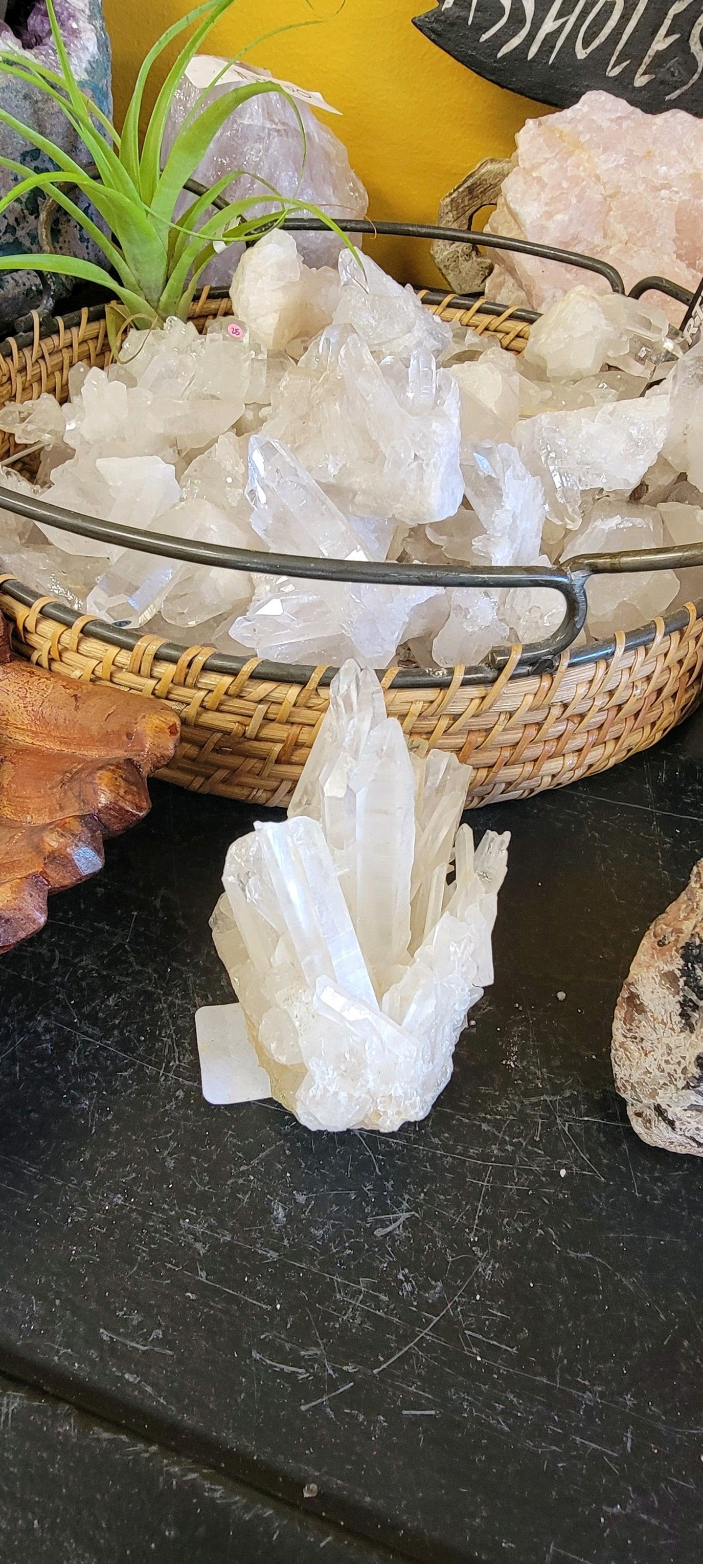 Cluster of white crystals on a dark surface, with a basket of similar crystals behind, displayed in a USA shop.