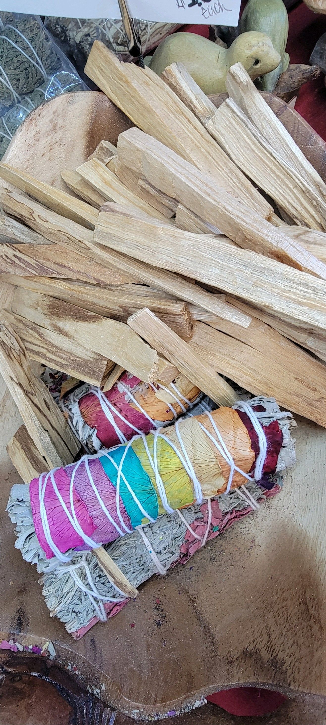 Bundles of sage wrapped in colorful thread with sticks in the background.