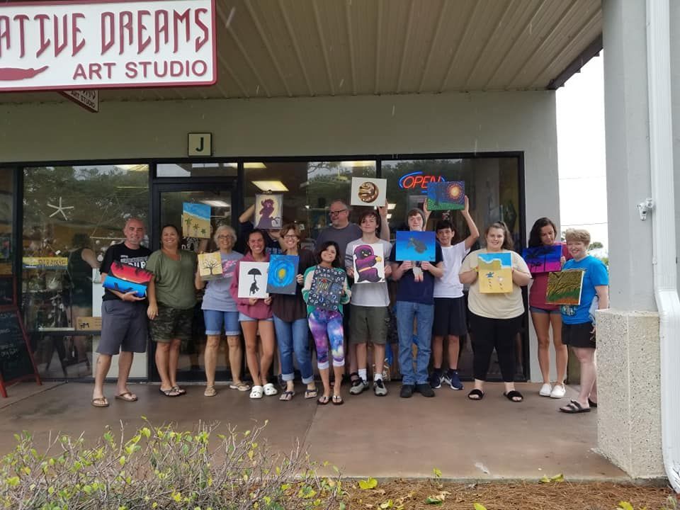 Group of people holding up paintings outside 