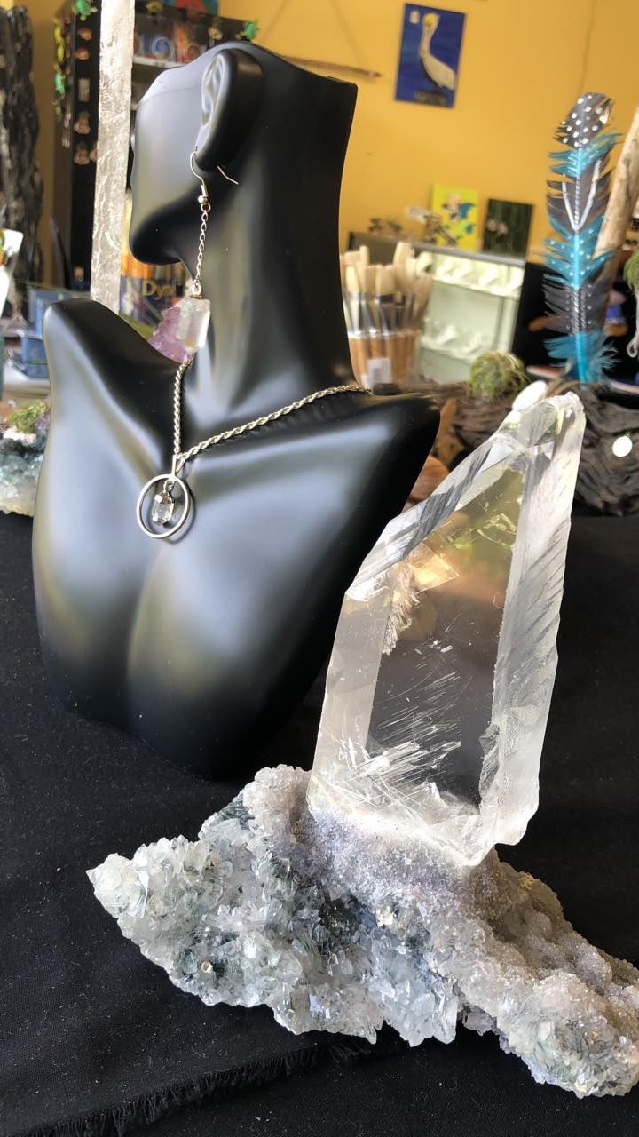 Black mannequin wearing jewelry, next to a large clear quartz crystal formation in a USA shop.