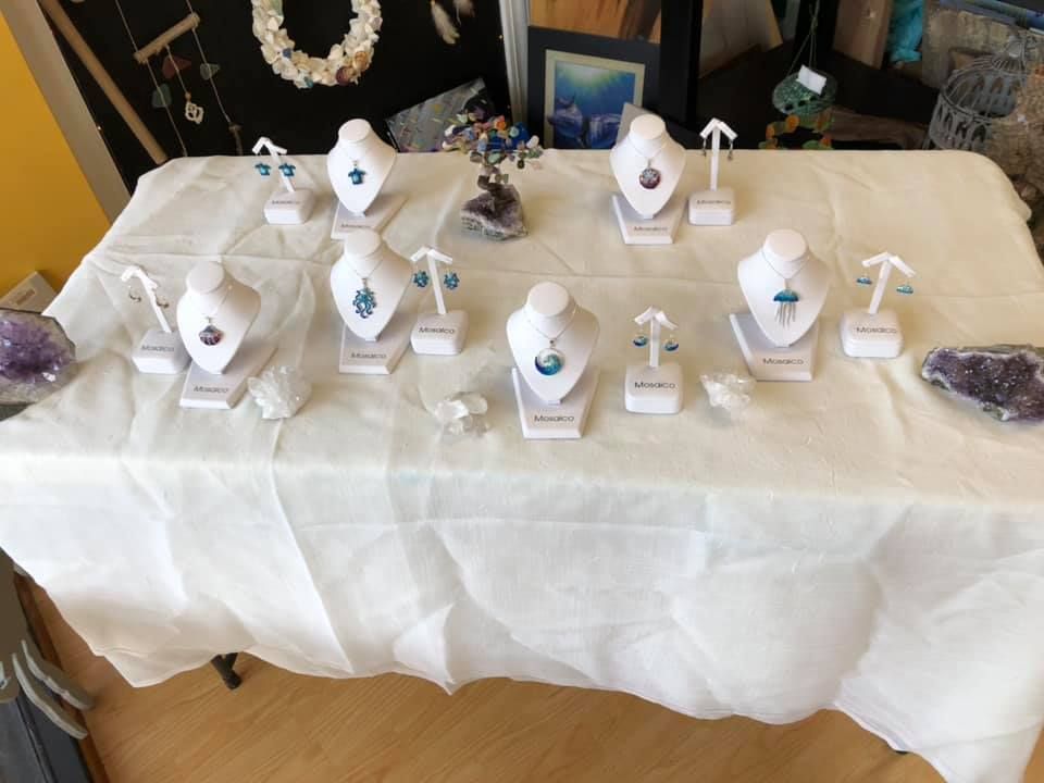 A jewelry display table with various necklaces and earrings on white stands and a draped cloth.